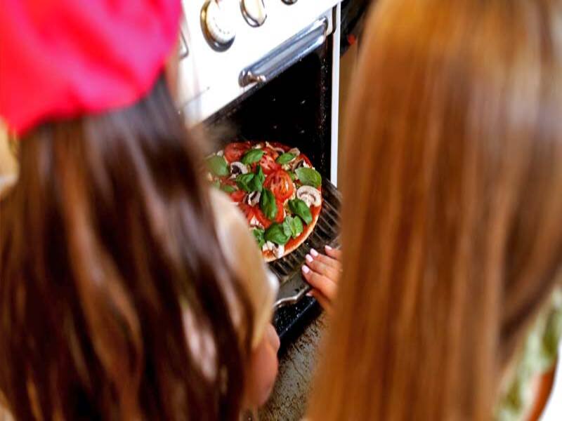 pessoas colocam pizza em um forno