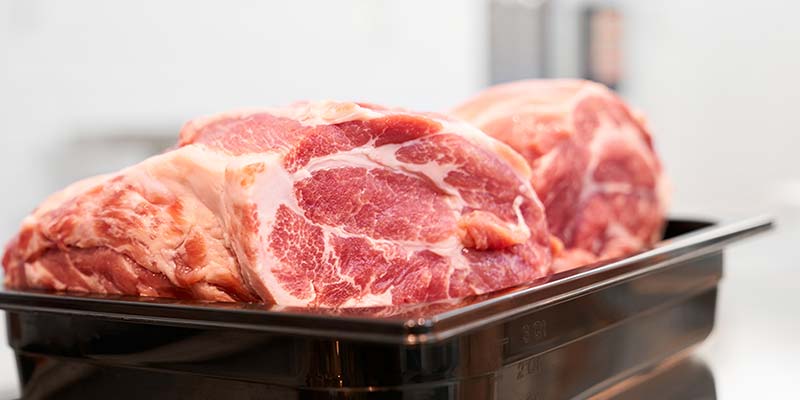 carne descongelada em uma forma preta