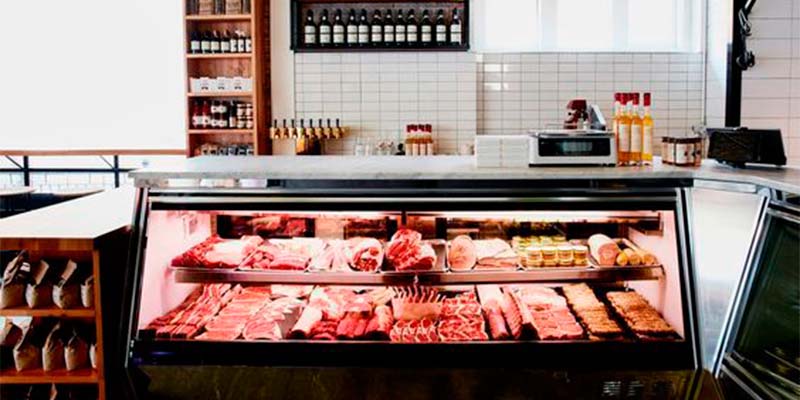 Expositor vertical cheio de carnes em um açougue