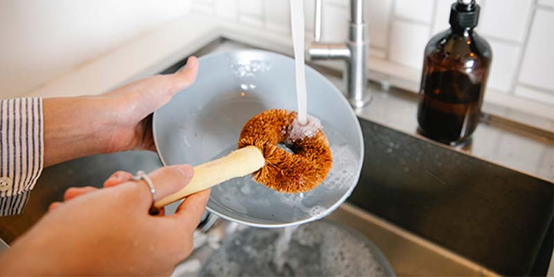 Mulher lavando prato branco com uma escova
