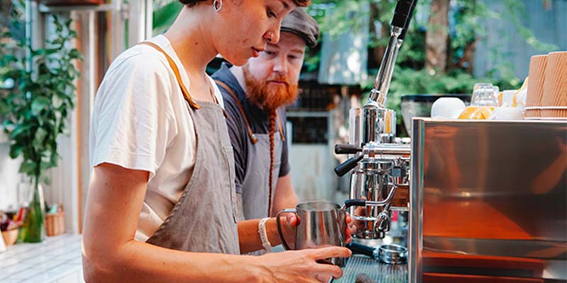 Homem ruivo observando uma mulher fazer café