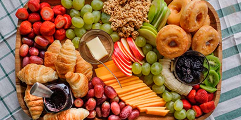 Tábua de frios cheia de alimentos diversos sobre uma mesa branca