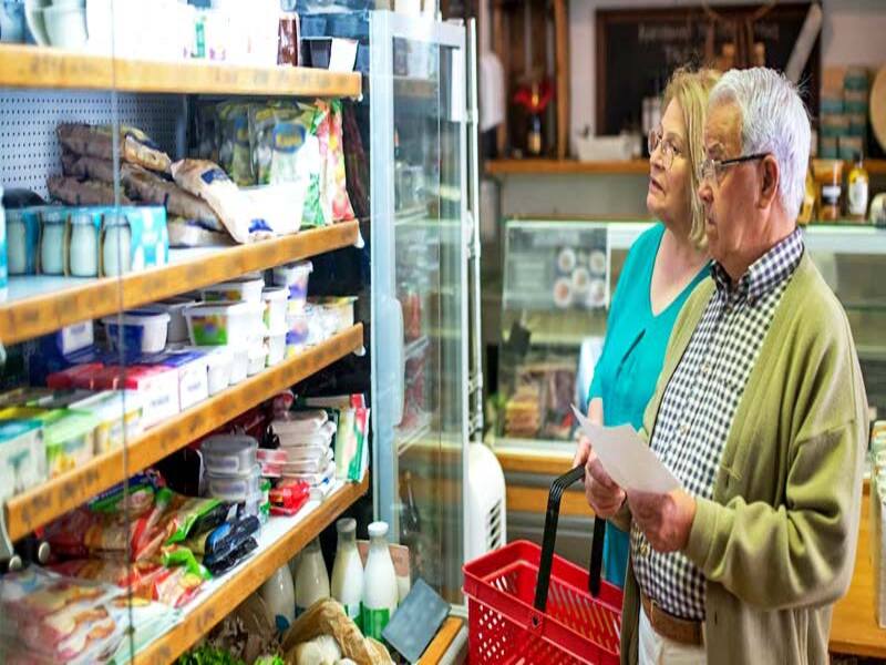 casal idoso analisa frios em um supermercado