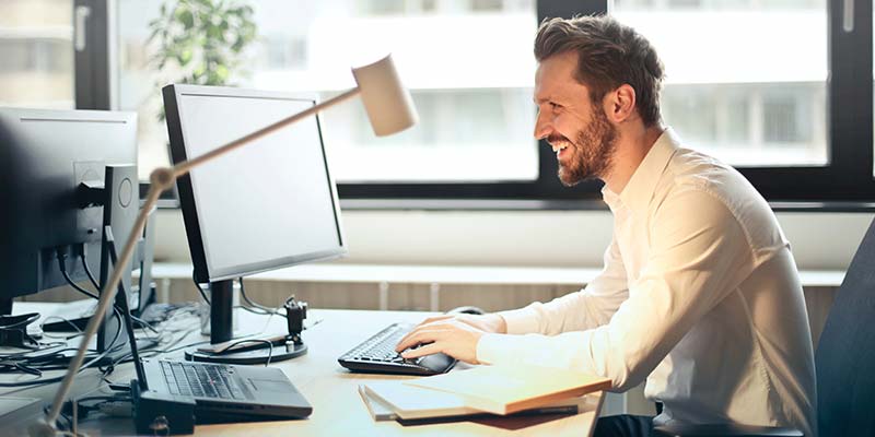 Homem sorrindo mexendo no computador