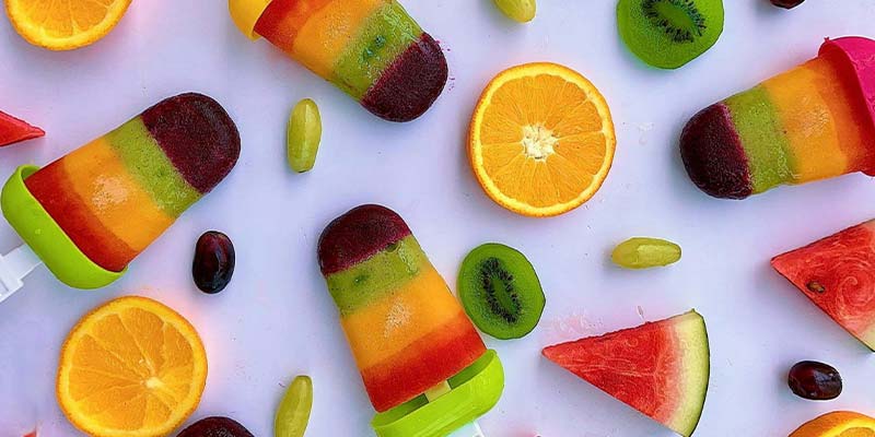 picolés coloridos com sabores de fruta em cima de uma mesa 